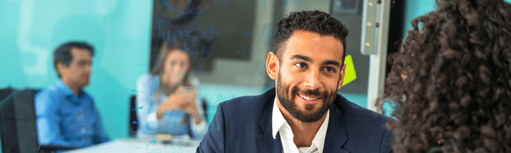 Man with a beard wearing a suit looking at a woman with her back to the camera
