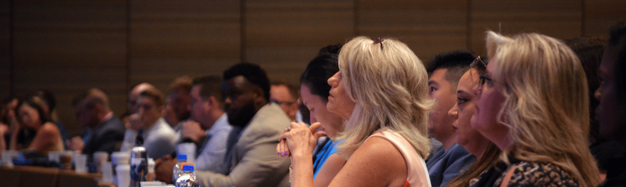 Woman in an audience watching a presentation while seated at a table 