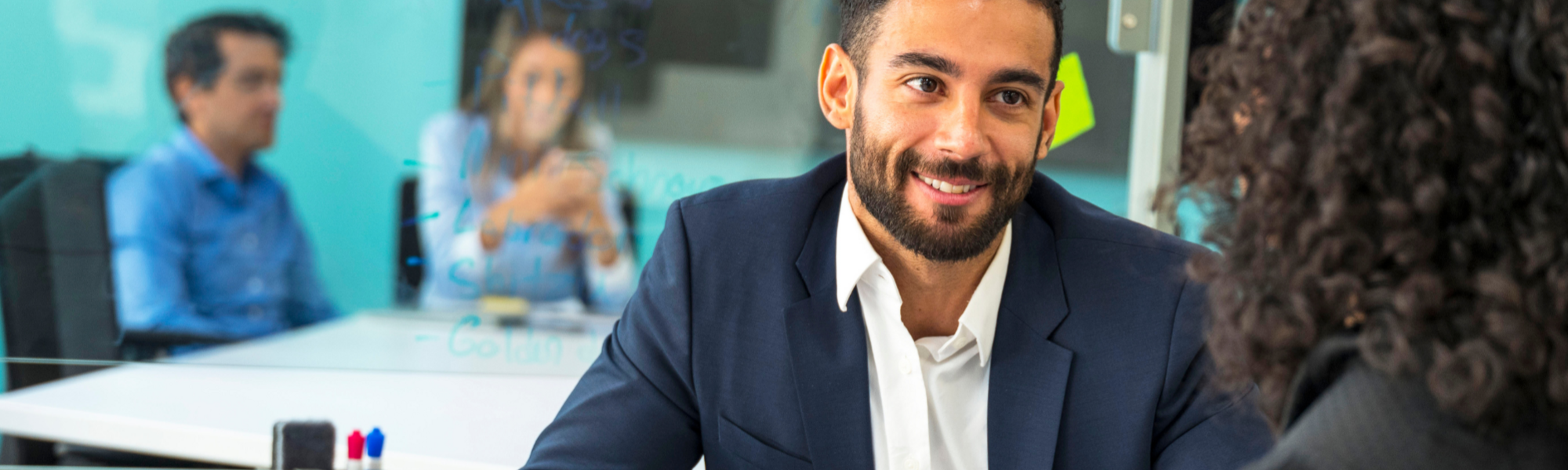Man with a beard wearing a suit looking at a woman with her back to the camera