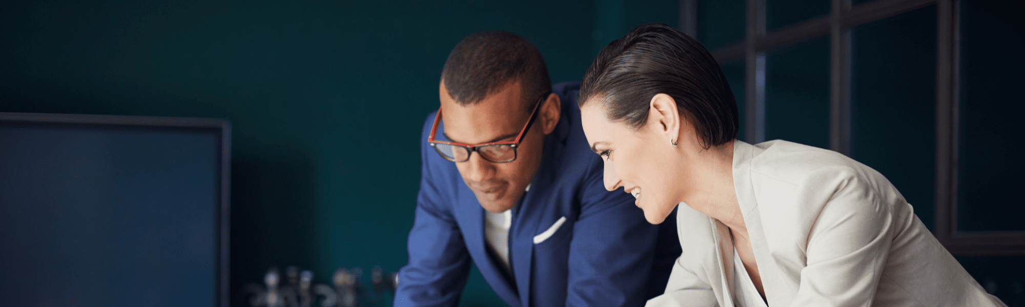 Professional woman and man with glasses looking at a laptop screen