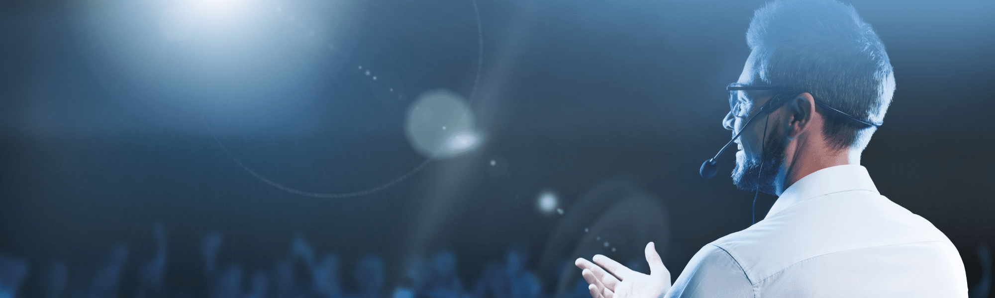 Man wearing a headset presenting to a large crowd